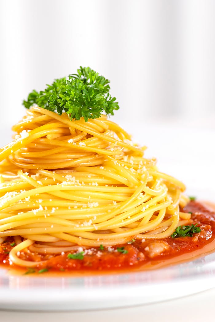Close-up of spaghetti with tomato sauce, garnished with herbs and cheese.